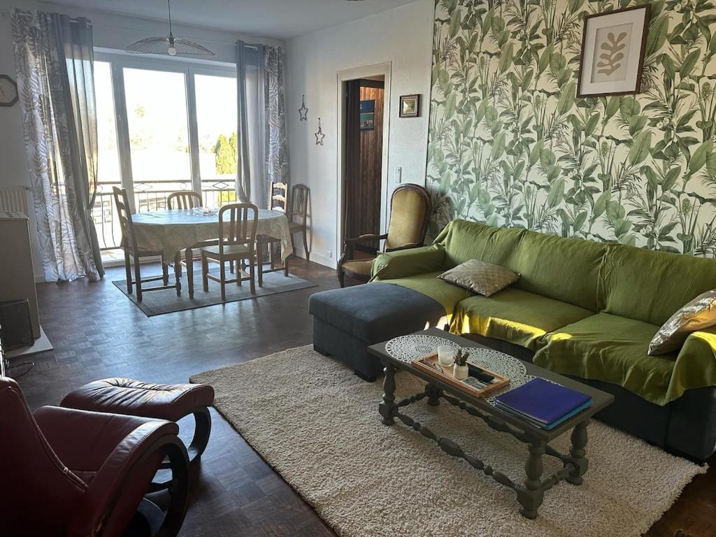 a living room with a green couch and a table at Maison de village proche du Lac de Vassivière in Peyrat-le-Château