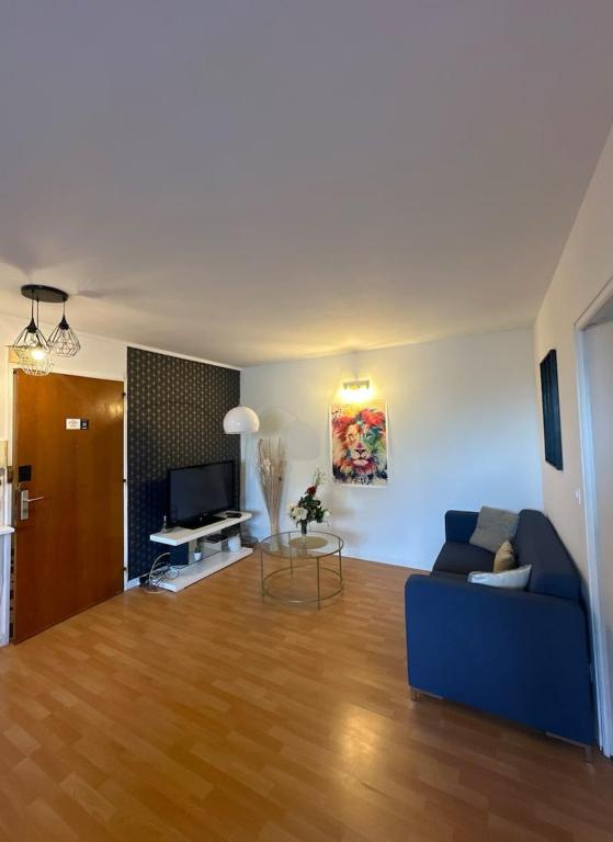 un salon avec un canapé bleu et une télévision dans l'établissement Simple et confortable, à Saint-Brieuc