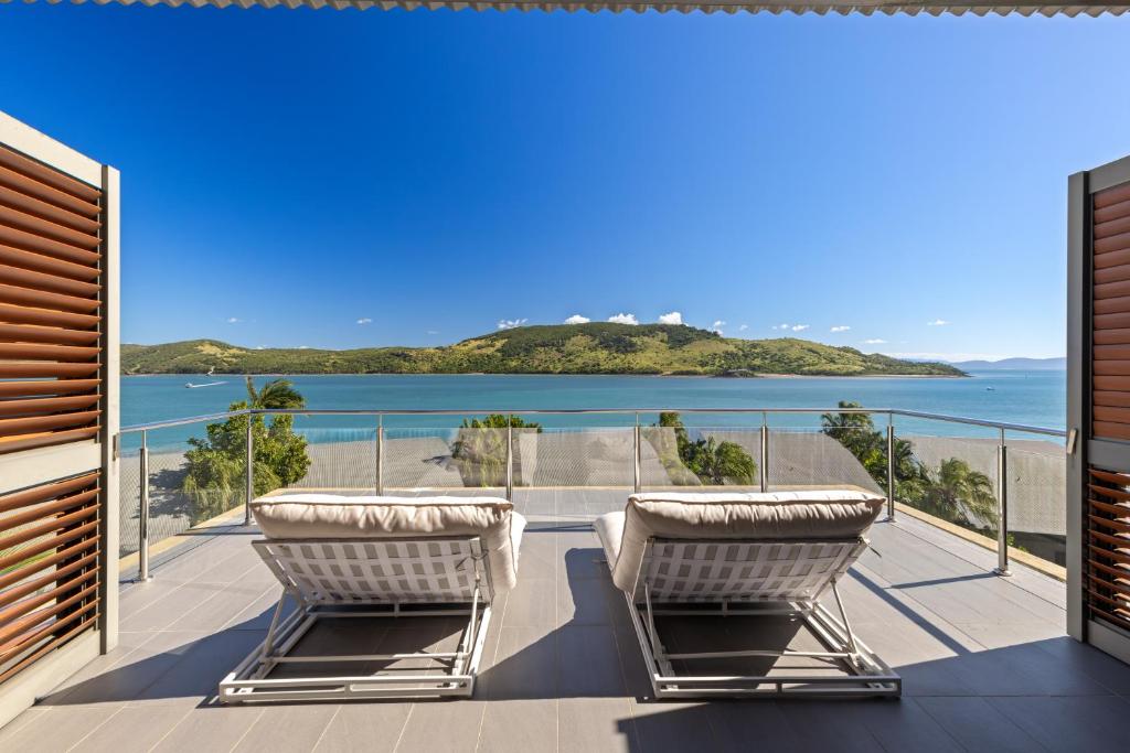 a balcony with two chairs and a view of the ocean at Yacht Club Villas on Hamilton Island by HIHA in Hamilton Island