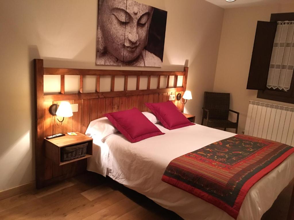 Ezcároz奥特索阿旅馆的一间卧室配有一张大床和两个红色枕头
