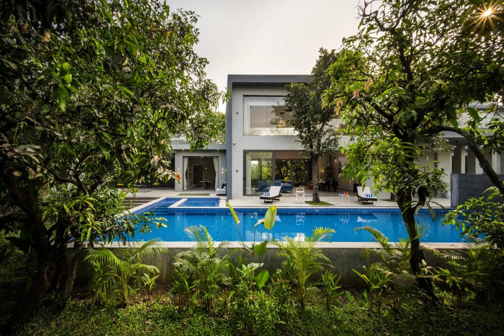 an external view of a house with a swimming pool at SaffronStays Six Degrees in Alibaug