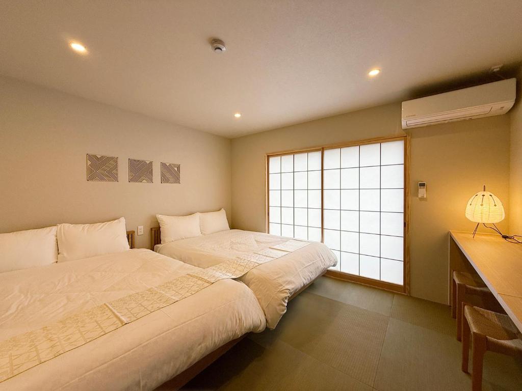 two beds in a bedroom with a large window at Celine Kanayama Building in Hiroshima