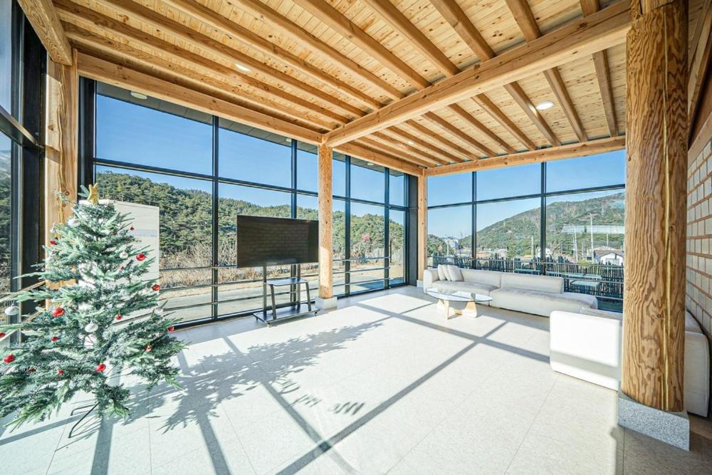 a living room with a christmas tree in a room with windows at Gyeongju Davulchon Pension in Gyeongju
