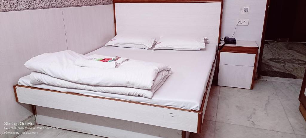 uma cama com lençóis brancos e toalhas em Mother Palace em Nova Deli