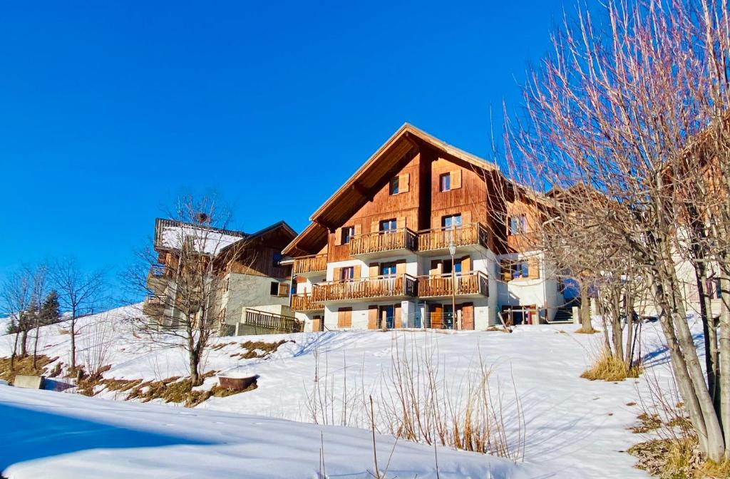 un grand bâtiment en bois dans la neige avec des arbres dans l'établissement Appartement Duplex 6 ou 7 personnes dans chalet à 250 m des pistes, à Albiez-Montrond