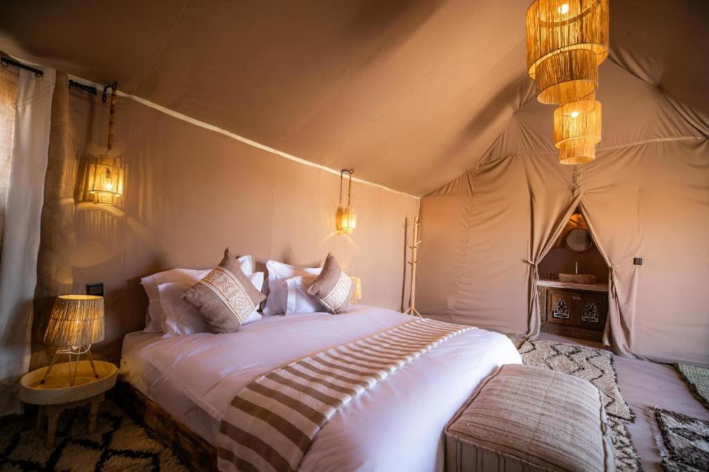 a bedroom with a large bed in a tent at Merzouga Desert Campsite &Activities in Merzouga