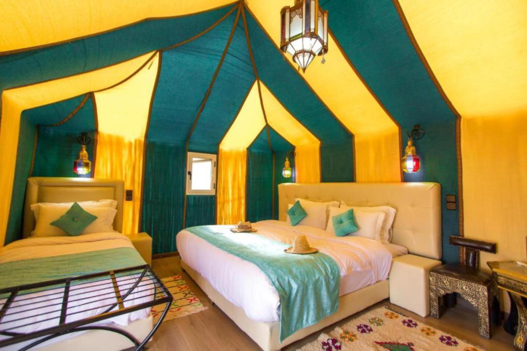 a bedroom with two beds and a canopy bed at Merzouga Desert Campsite &Activities in Merzouga