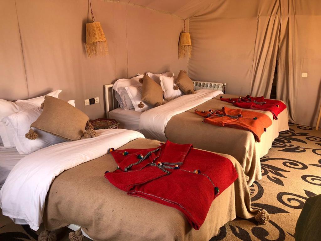 a group of four beds in a room at Merzouga Desert Campsite &Activities in Merzouga