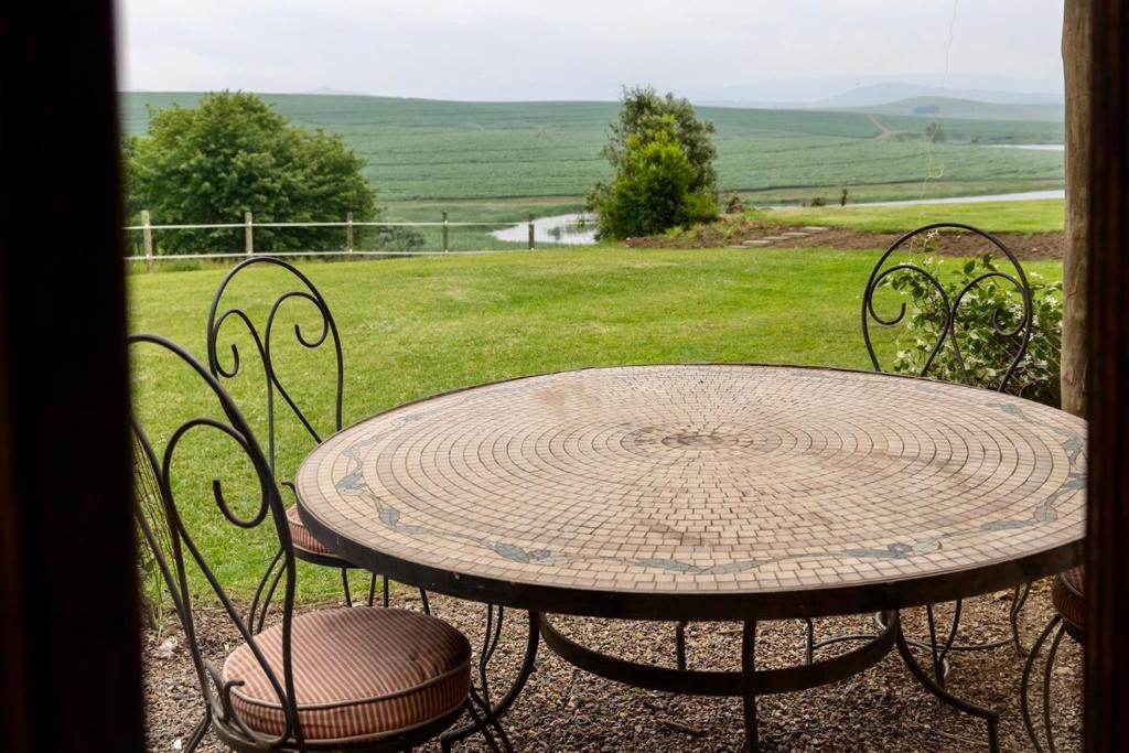 a table and chairs with a view of a field at Ebernburg Cottage in Nottingham Road