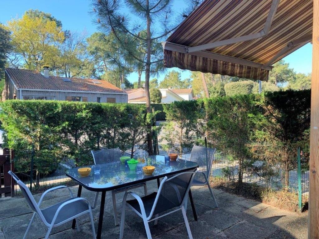 une table et des chaises sur une terrasse sous un parasol dans l'établissement La Palmyre - AGREABLE VILLA MITOYENNE - PISCINE COLLECTIVE, aux Mathes