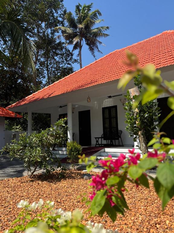 a white house with a red roof and some flowers at Marari Arattukulam Villa in Mararikulam