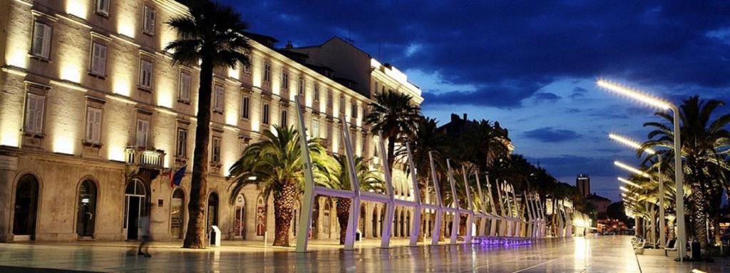 una calle con palmeras frente a un edificio en Luxury rooms Skystar-Split, en Split