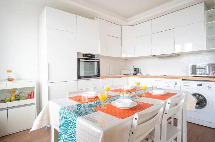 - une cuisine blanche avec une table, des chaises et des boissons dans l'établissement La Passerelle - Petit Balcon, au Havre