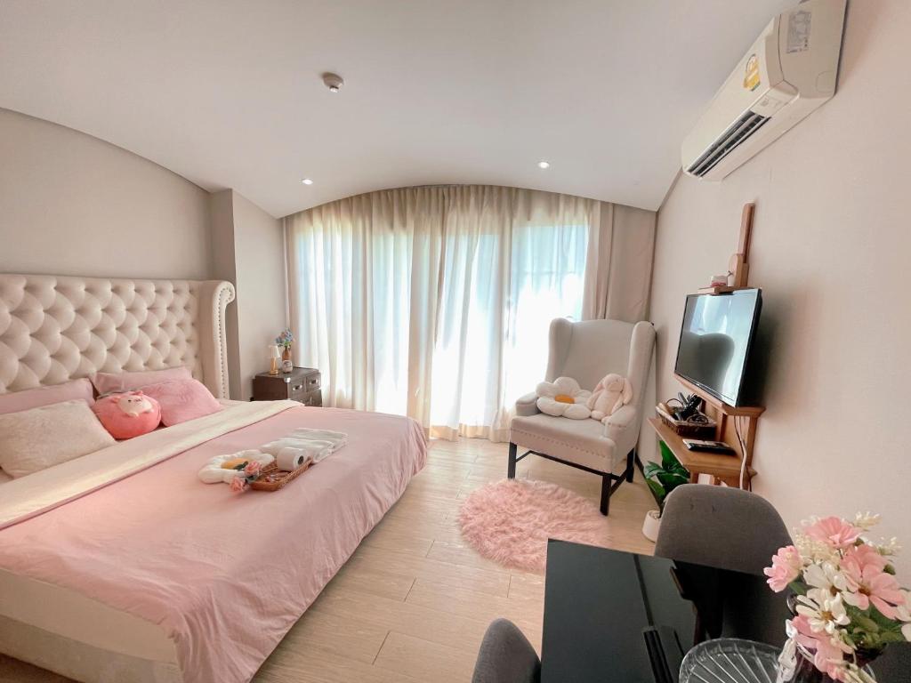 a bedroom with a bed and a tv and a chair at Venetian Signature Condo Pattaya in Jomtien Beach