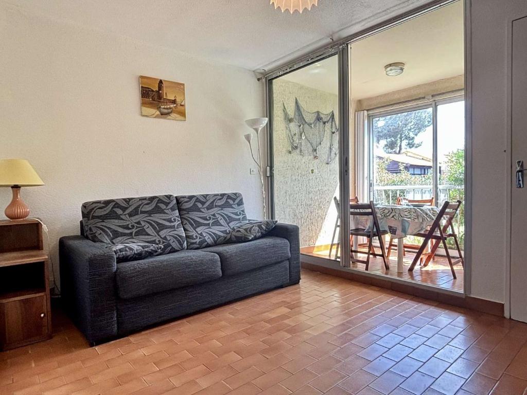 un salon avec un canapé et une porte coulissante en verre dans l'établissement Appartement Studio cabine ARGELES SUR MER AR020-033, à Argelès-sur-Mer