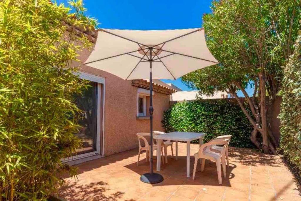 une table et des chaises avec un parasol sur une terrasse dans l'établissement Presqu'île de Giens, Joli T2 à 5 minutes de la plage à pieds, à Hyères