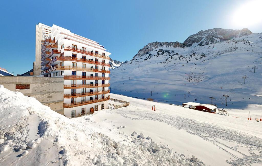 un bâtiment dans la neige à côté d'une montagne enneigée dans l'établissement 2 Bedroom Nice Apartment In La Mongie, à La Mongie