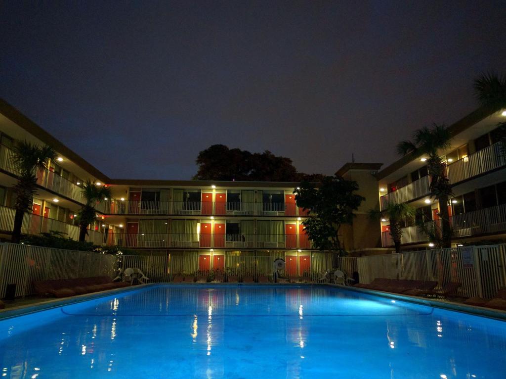 Una gran piscina frente a un edificio por la noche. en Red Carpet Inn Airport Fort Lauderdale, en Fort Lauderdale