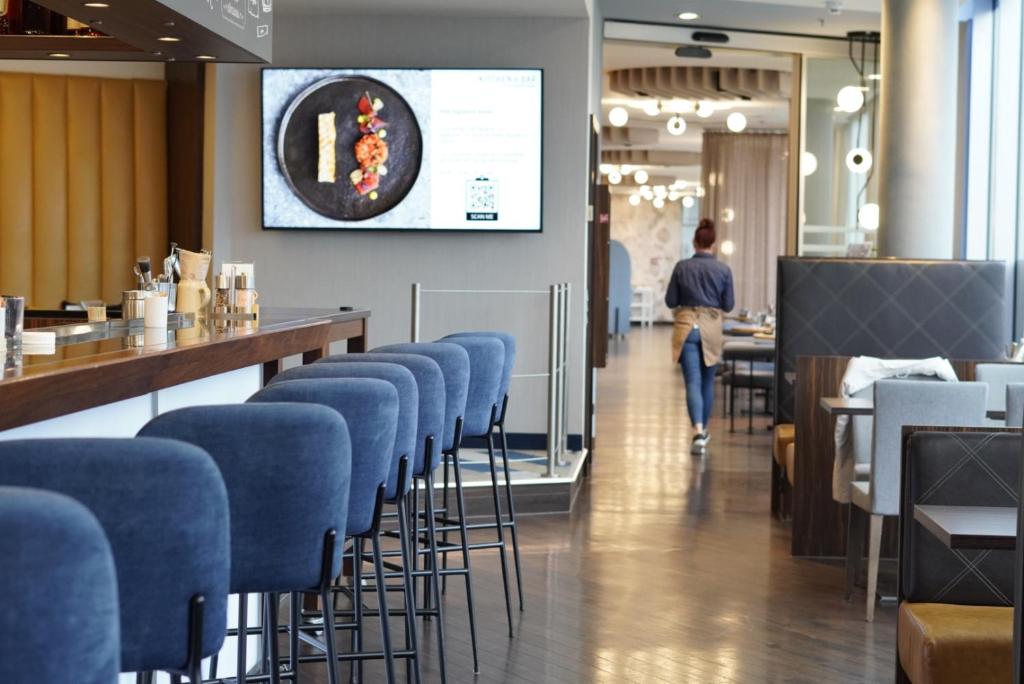 um bar com bancos azuis num restaurante com um homem a passar em Courtyard by Marriott Linz em Linz