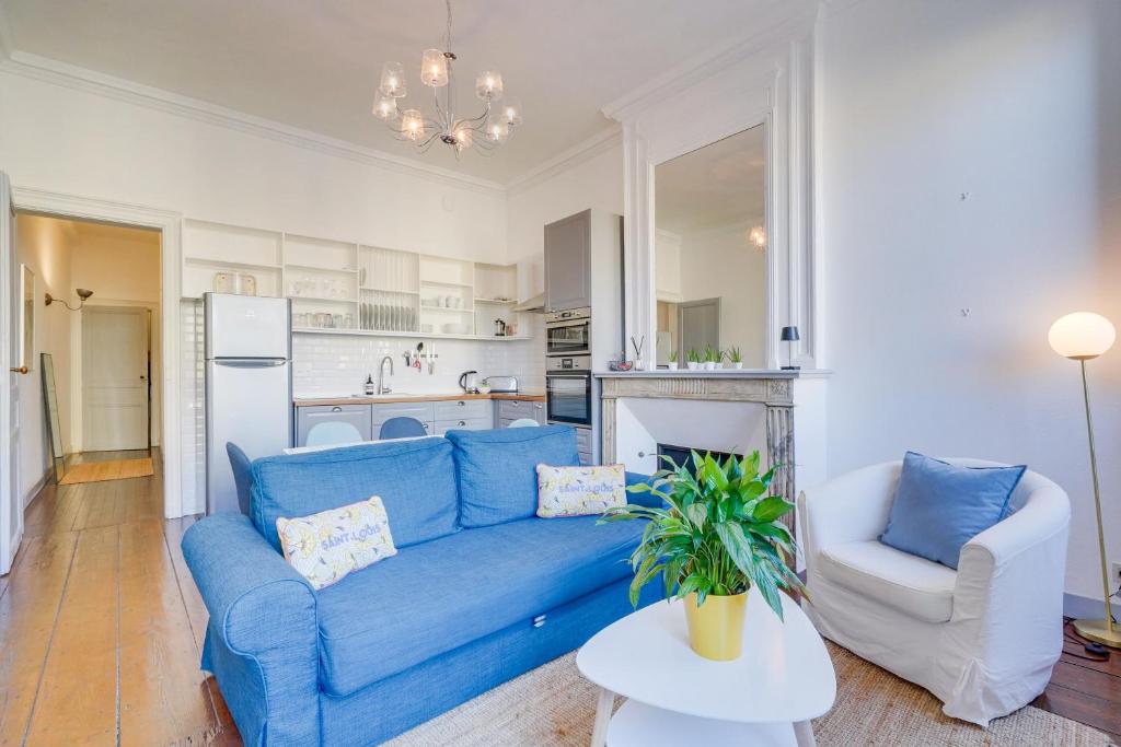 un salon avec un canapé bleu et une cuisine dans l'établissement MDOR Le Nid Bleu - Au coeur de Bordeaux, à Bordeaux