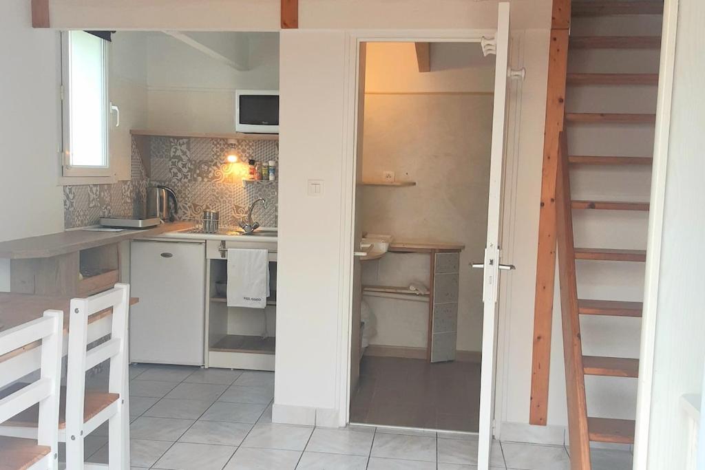 une cuisine avec une porte s'ouvrant sur une cuisine avec un évier dans l'établissement studio, 2 personnes lit en mezzanine, à Angers