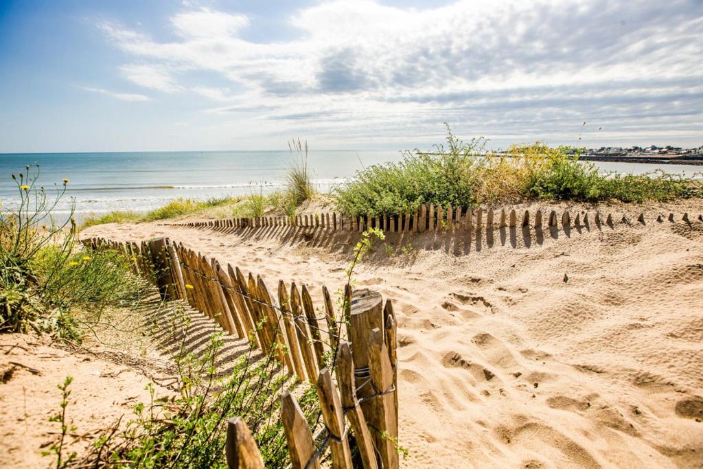 une clôture en bois sur une plage de sable avec l'océan dans l'établissement Maison de caractère au coeur de Saint Gilles Croix de Vie, à Saint-Gilles-Croix-de-Vie