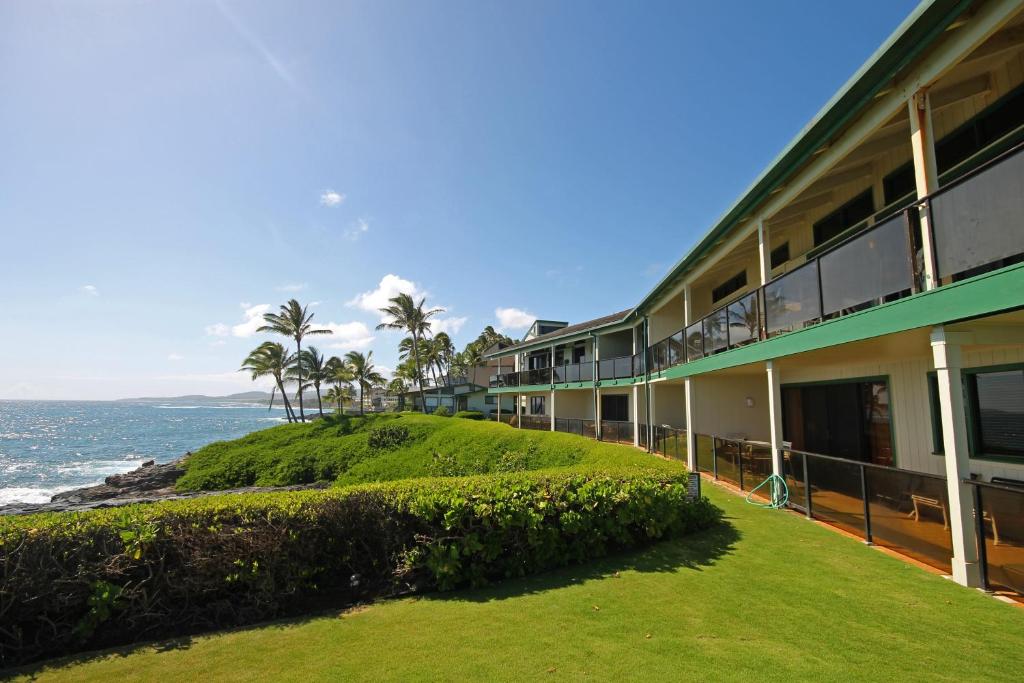 a building with a green hill next to the ocean at CASTLE at Makahuena at Po'ipū in Koloa