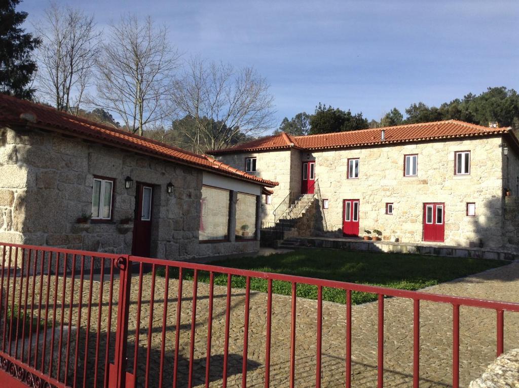 zwei Steingebäude mit roten Türen und einem Zaun in der Unterkunft Casas do Eido e Casa da Viúva in Celorico de Basto