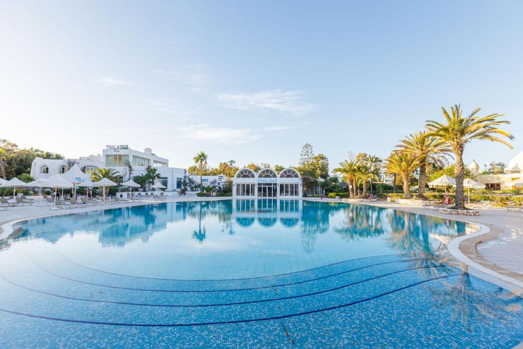 a large swimming pool at a resort with palm trees at Iris Hotel & Thalasso in Taguermess