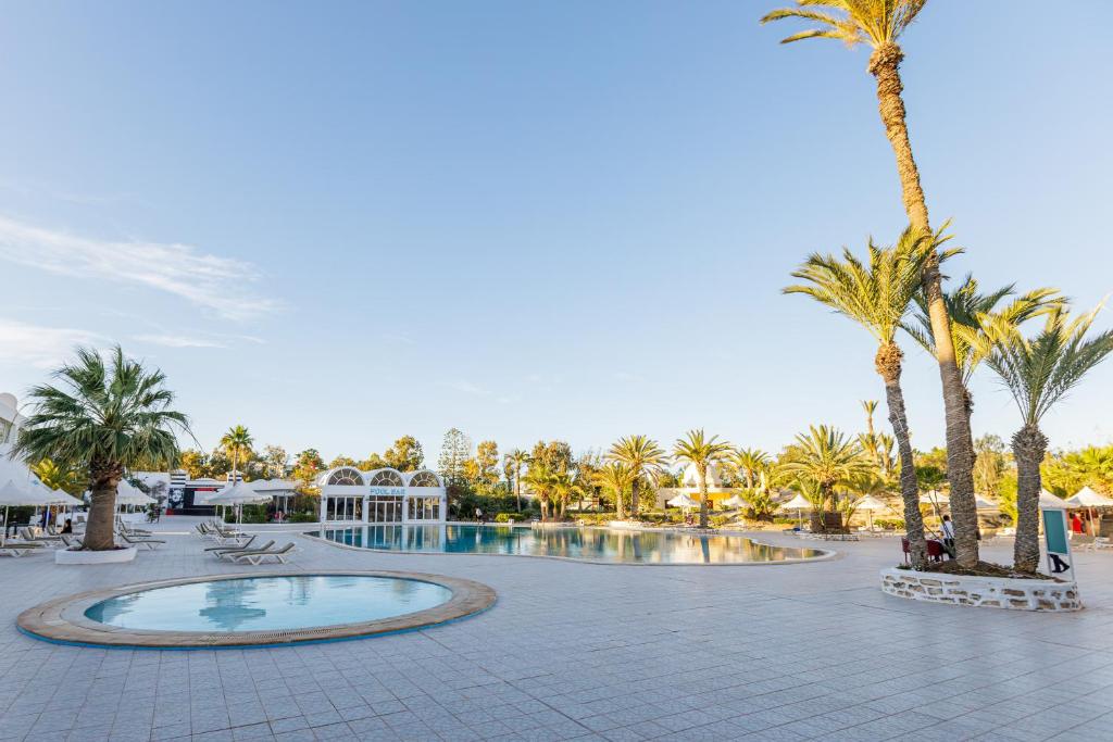 a resort with a swimming pool and palm trees at Iris Hotel & Thalasso in Taguermess