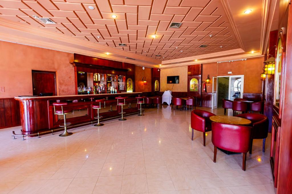 a bar in a restaurant with red chairs and tables at Iris Hotel & Thalasso in Taguermess