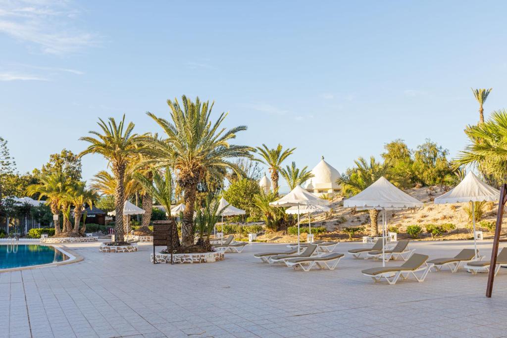 a resort with a pool and chairs and palm trees at Iris Hotel & Thalasso in Taguermess