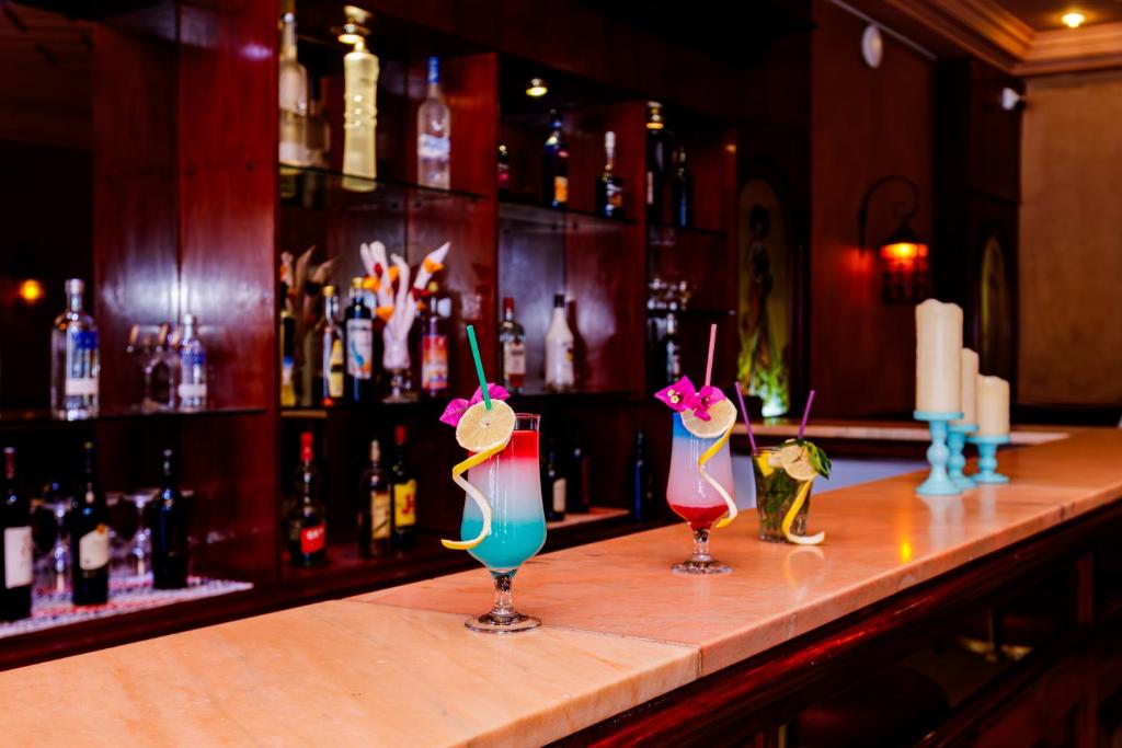 three cocktails sitting on a bar in a pub at Iris Hotel & Thalasso in Taguermess