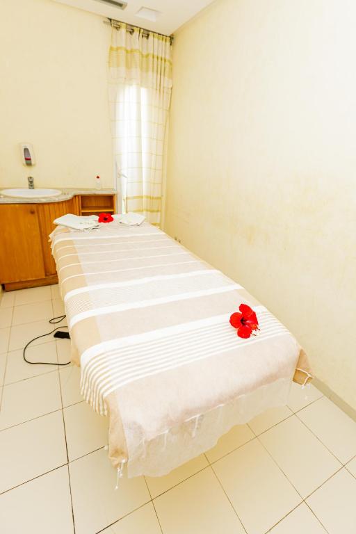 a room with a bed with red flowers on it at Iris Hotel & Thalasso in Taguermess