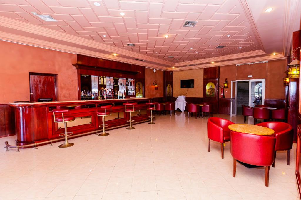 a bar in a restaurant with red chairs and tables at Iris Hotel & Thalasso in Taguermess