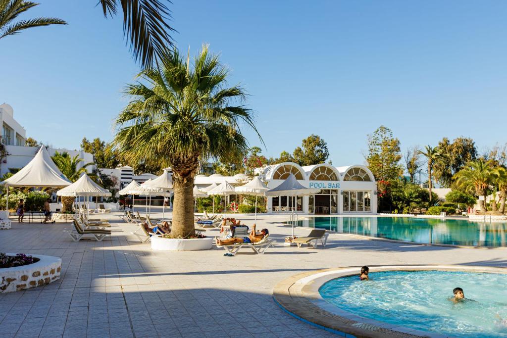a pool at a resort with people sitting around it at Iris Hotel & Thalasso in Taguermess
