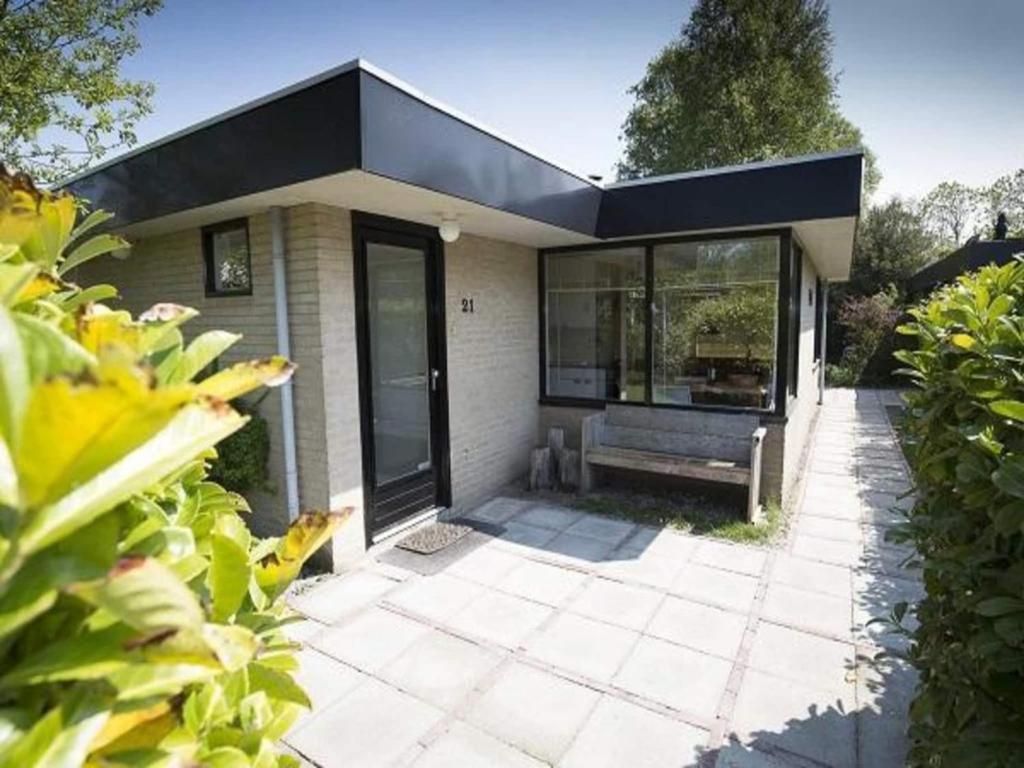 a house with a bench in front of it at Family bungalow with garden in Sint Maartenszee