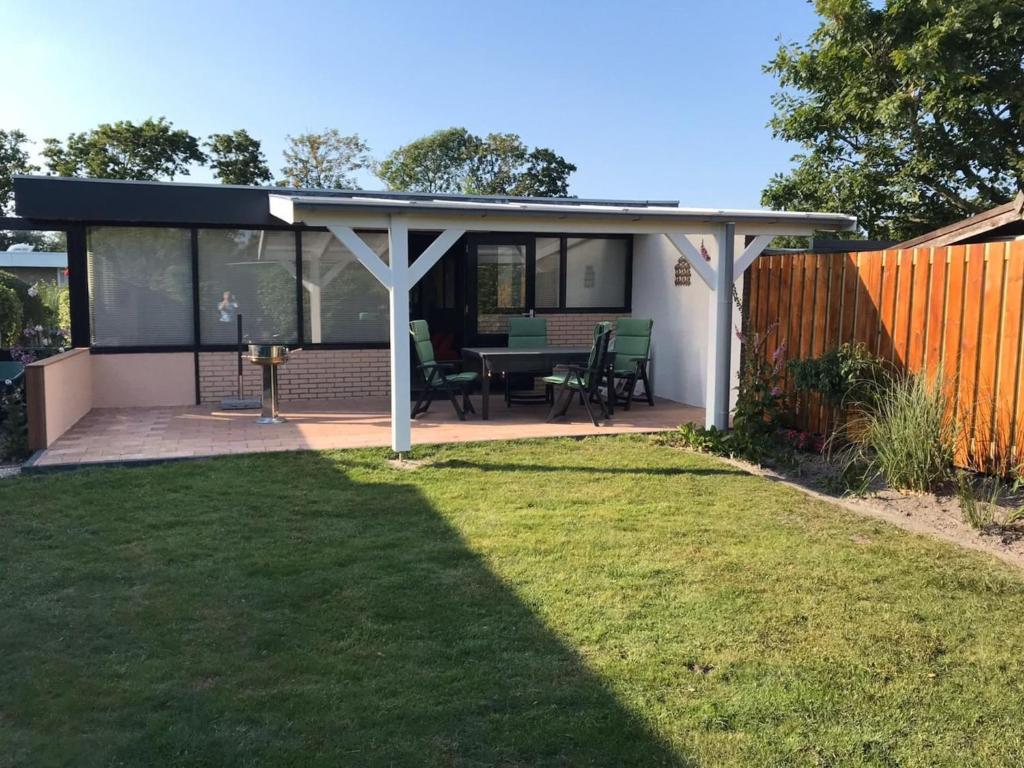 a covered patio with a table and chairs at Bungalow in Wildrijk with Fenced Garden in Sint Maartenszee