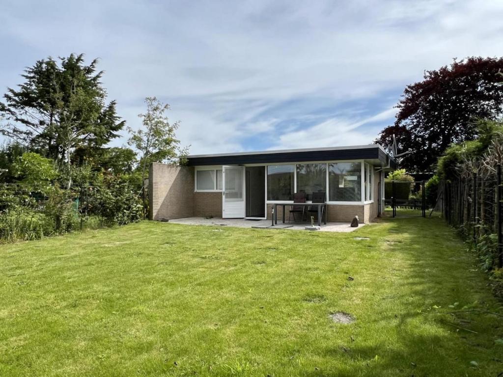 a small house with a lawn in front of it at Pet-friendly bungalow near Beach in Sint Maartenszee