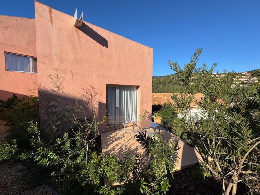 un bâtiment en briques avec des arbres devant lui dans l'établissement Maison 2 personnes Chateaubriand, à Hyères