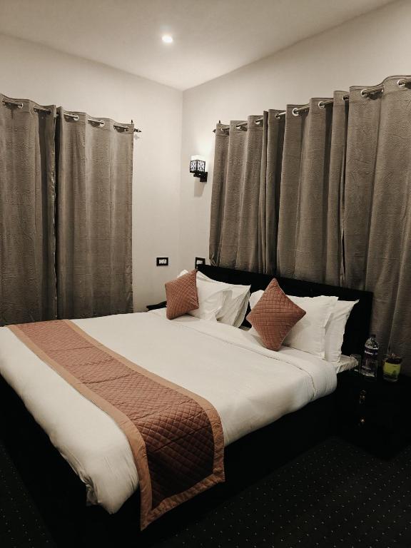 a bedroom with a large bed with brown curtains at Gulmarg Orchard in Gulmarg