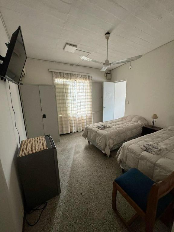 a room with two beds and a flat screen tv at Luminoso y Acogedor Espacio in Paysandú