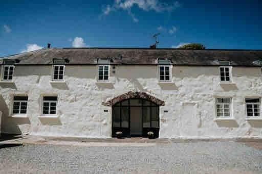 a large white stone building with a large door at Courtyard Cottage with hot tub and walled garden in Hubberston