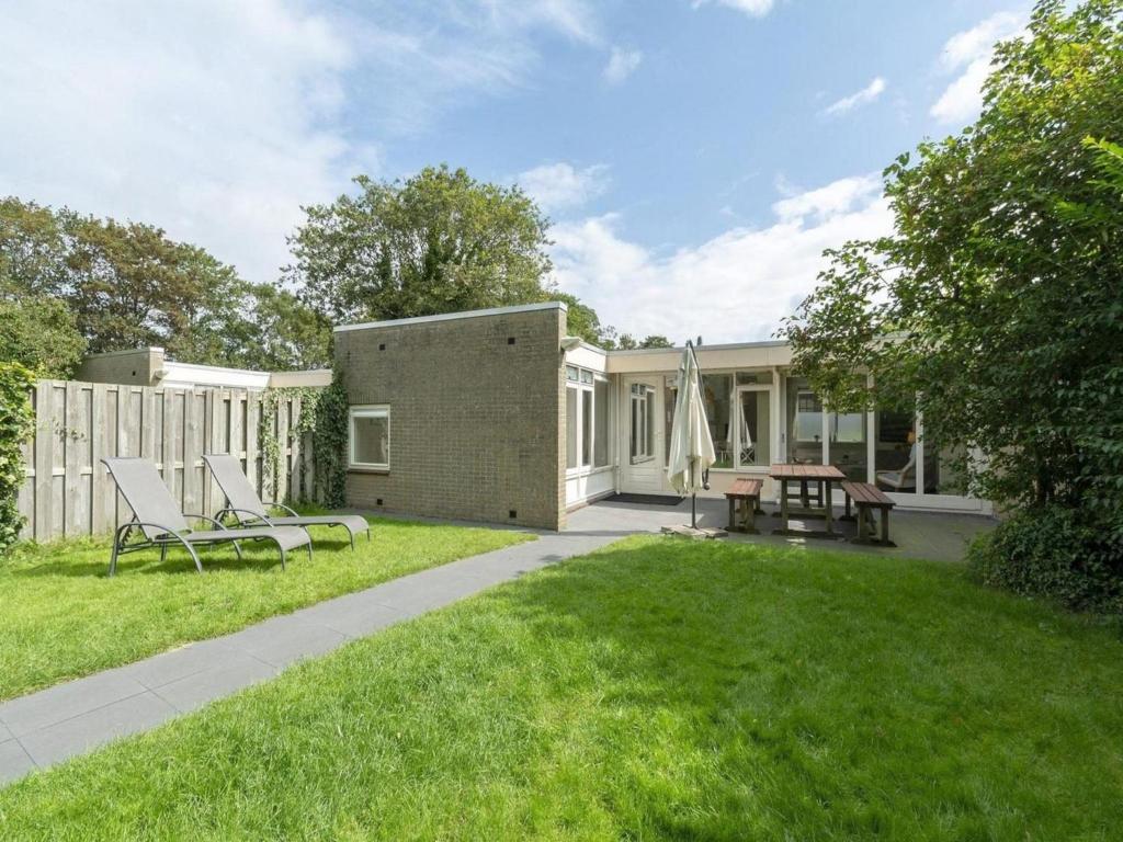 une arrière-cour d'une maison avec deux chaises et une table dans l'établissement Nice bungalow near beach for 5 guest, à Sint Maartenszee