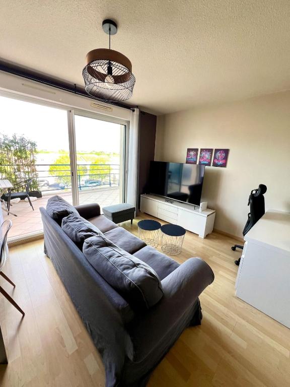 un salon avec un canapé et une grande fenêtre dans l'établissement Le Corsaire - Appartement spacieux avec terrasse, à Aytré