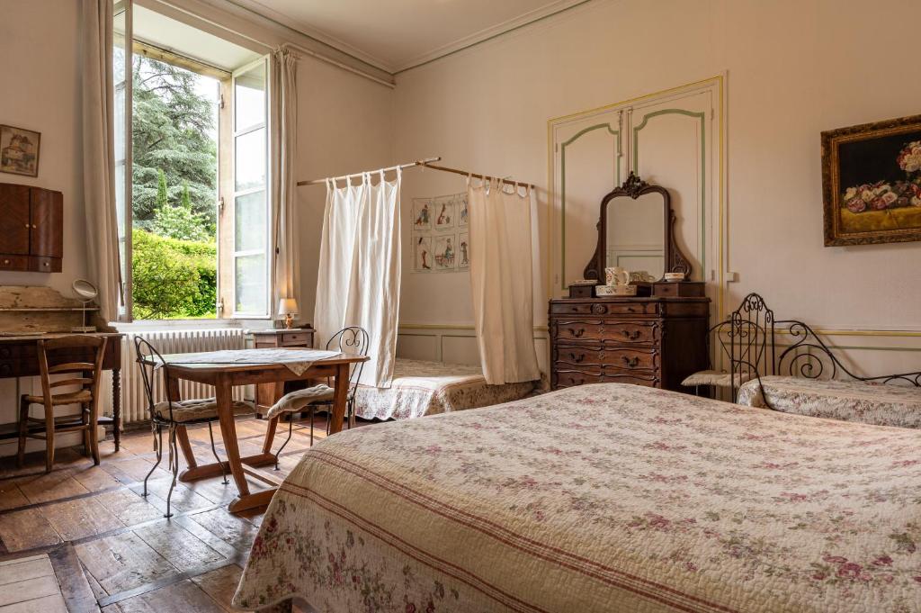 a bedroom with a bed and a table and a window at La Maison du Notaire Royal in Sarlat-la-Canéda