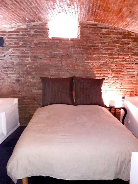 une chambre avec un lit avec un mur de briques dans l'établissement Appartement 2 bedrooms Hyper quiet PEDESTRIAN HISTORIC CENTER, à Toulouse