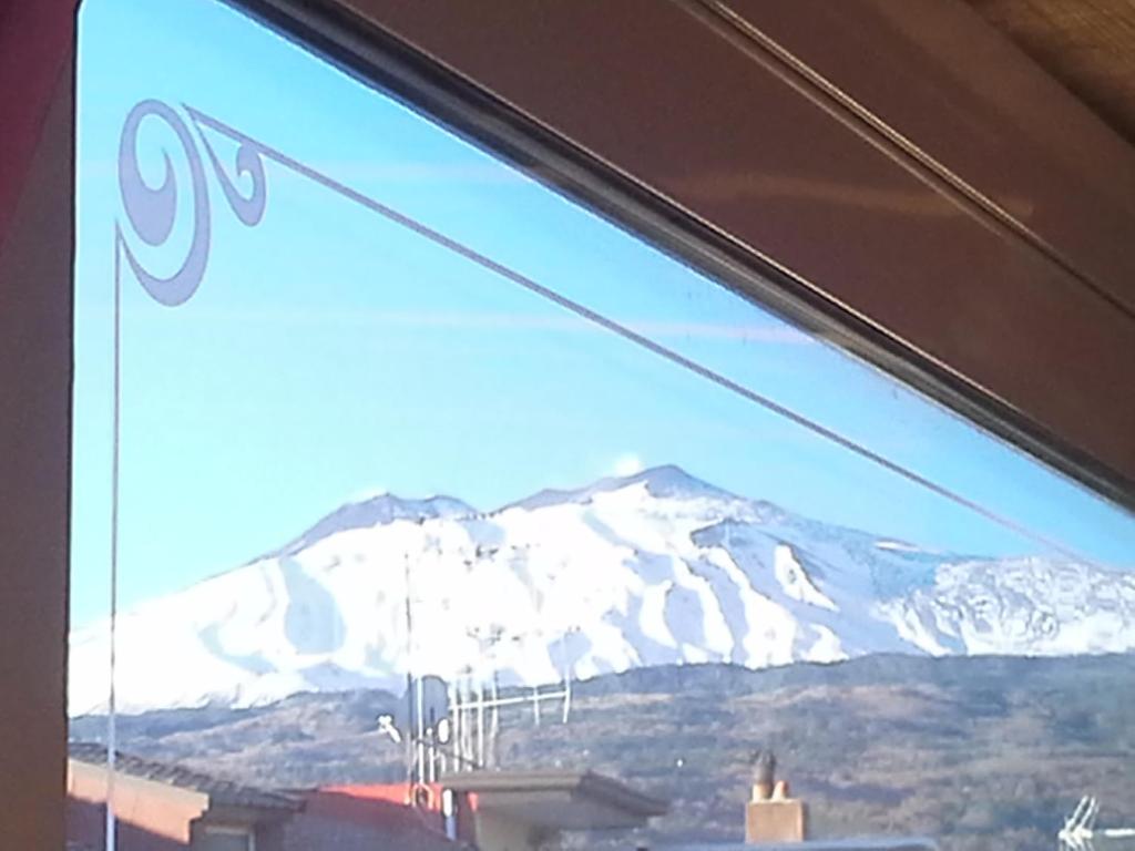 a view of a snow covered mountain through a window at La Casa Dei Cestai in Linguaglossa