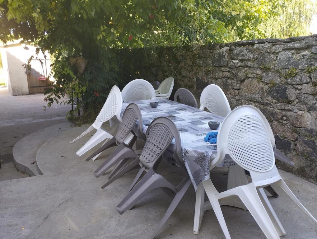 a table with white chairs and a stone wall at Maison avec jardin in Saint-Amand-sur-Sèvre