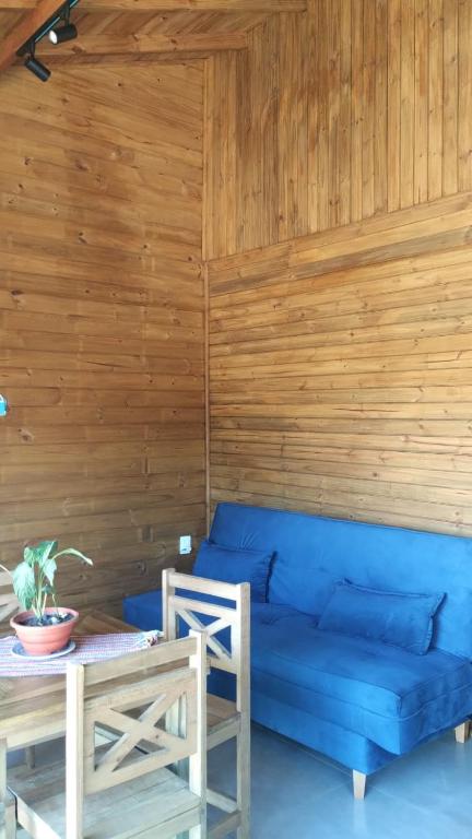 een blauwe bank in een kamer met een houten muur bij Residencial Bambu in Garopaba